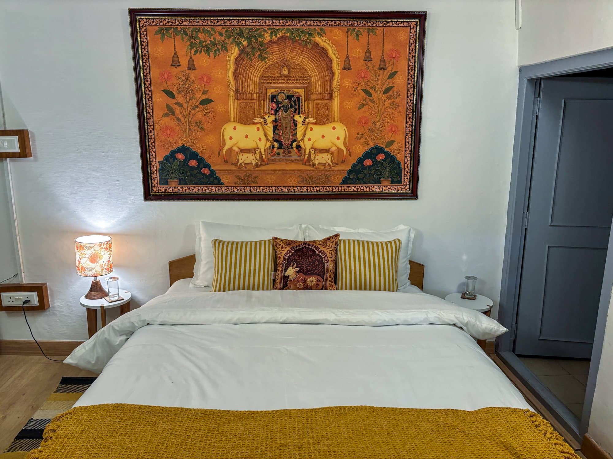 A bedroom at Shail Shikhar with a gold Pichwai above the bed