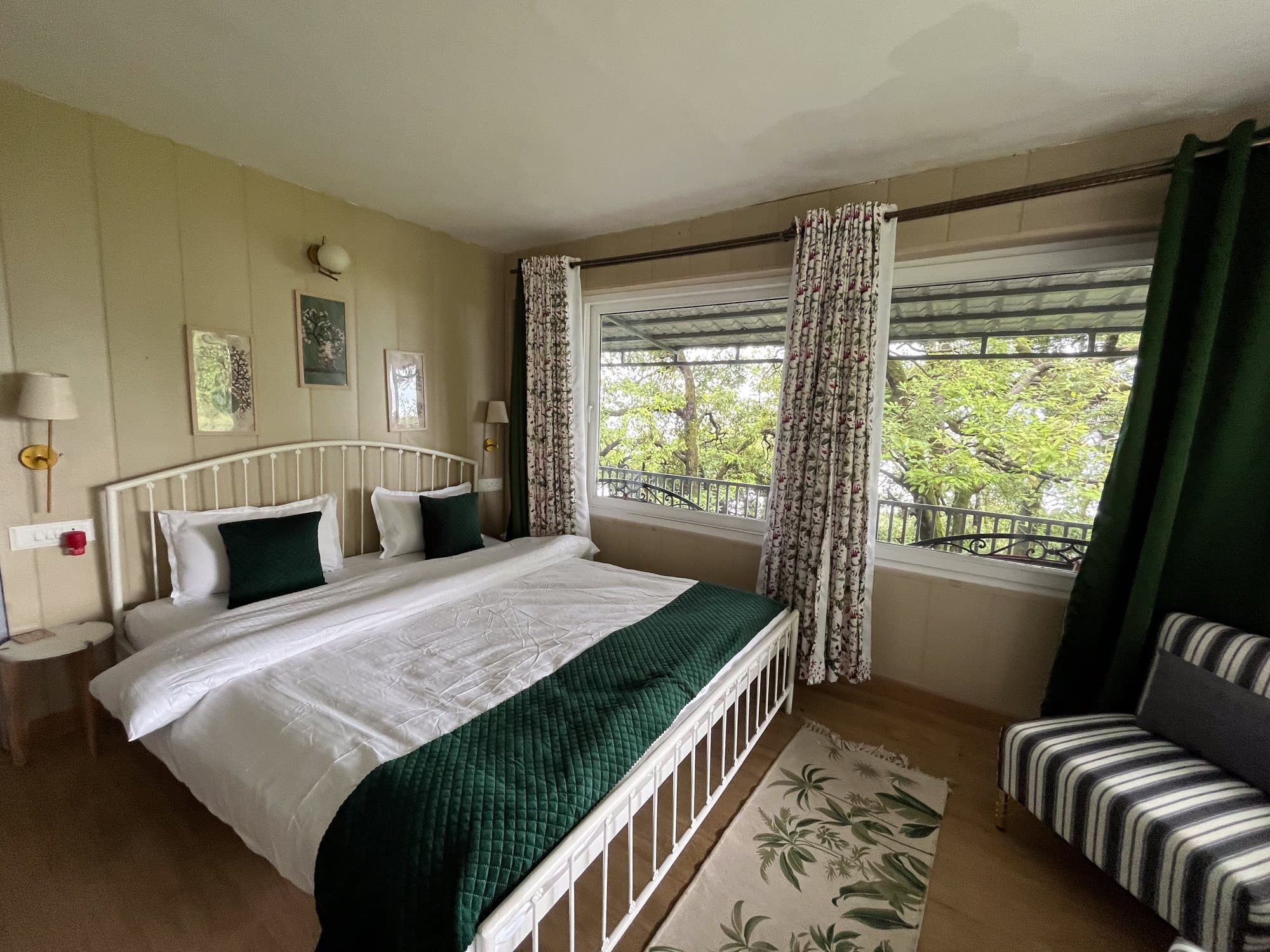 A bedroom at Shail Shikhar with corner windows and a green throw