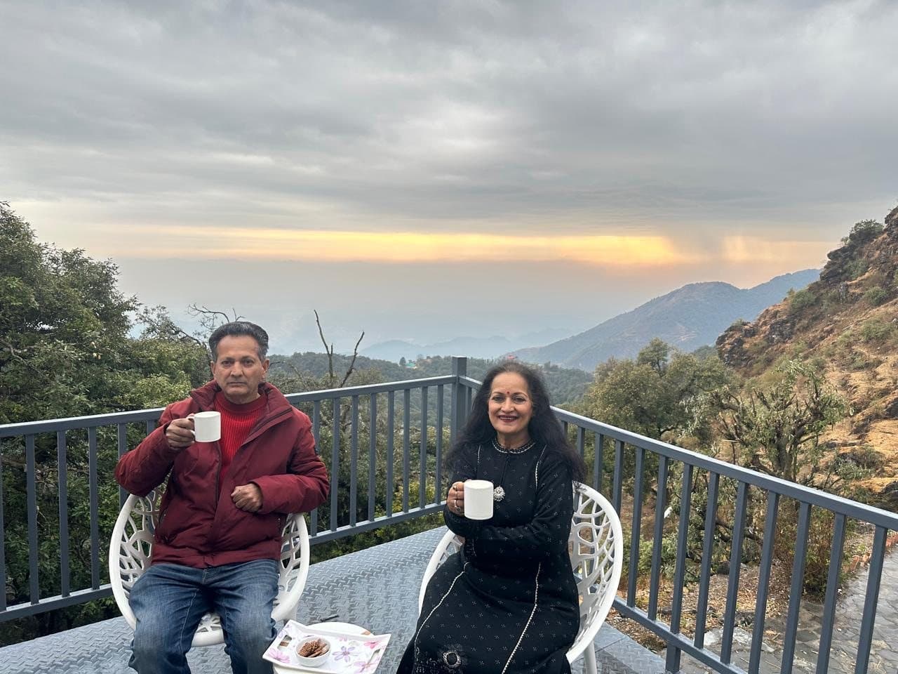 Himanshu Bhatt and Himani Shivpuri with morning tea on the terrace at Shail Shikhar, the valley behind them